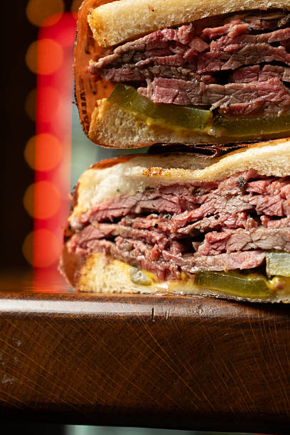 sliced roast beef sandwich with shredded lettuce, tomato, and red onion
