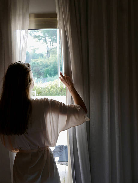 istock Young woman opening the curtains window 2219913716