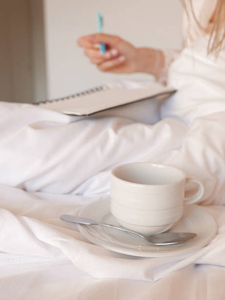 istock Woman having coffee and writing in her bed 2219913755