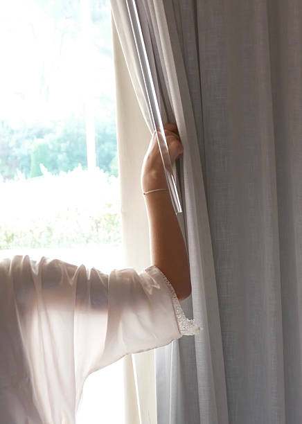 istock Young woman opening the curtains window 2219913888