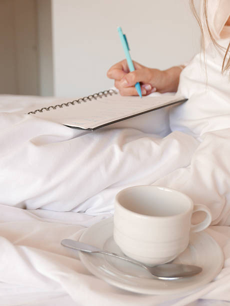 istock Woman having coffee and writing in her bed 2219913952