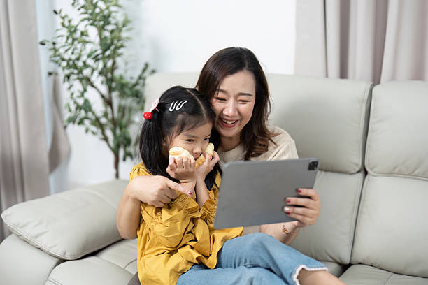 istock Mother and Daughter Enjoying Tablet Time. Sharing smiles and snacks in a cozy setting. 2219914251