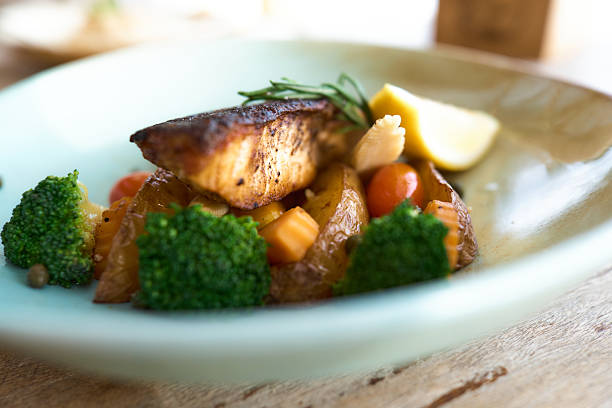 Close up of roasted slice of fish with vegetables in a plate.