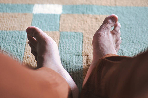 istock Person's Bare Feet Resting on Soft Colored Striped Rug Indoor Setting 2219914836