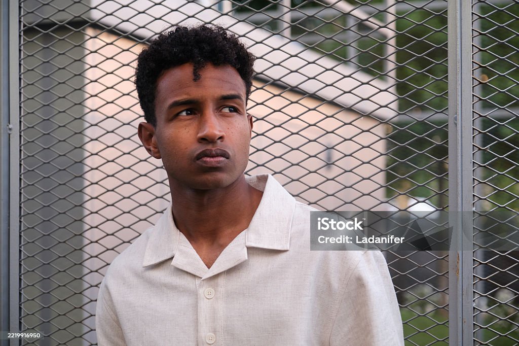 Junger Mann, der wegschaut und vor einem Metallzaun in der Stadt posiert - Lizenzfrei 25-29 Jahre Stock-Foto Junger Mann, der wegschaut und vor einem Metallzaun in der Stadt posiert - Lizenzfrei 25-29 Jahre Stock-Foto