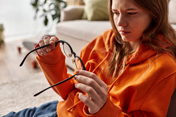 istock Young woman reflects at home while examining her glasses during a sunny day 2219922089