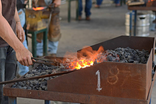A farrier pulls a red hot horseshoe from the forge.