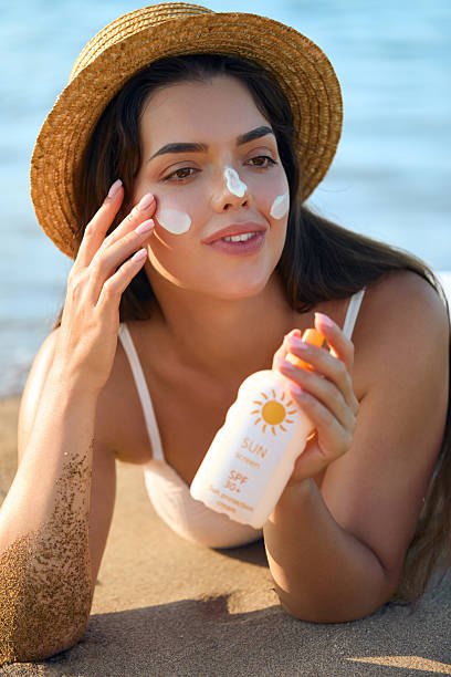 istock Smiling woman applying sunscreen on beach at sunset in bikini. 2219923221