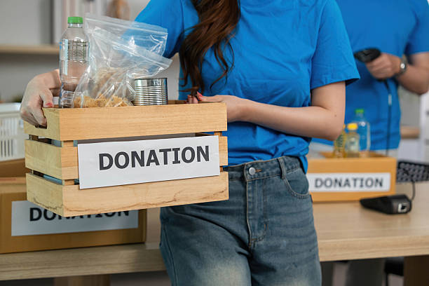 istock Donation and Generosity. Volunteer holding a donation box filled with essential items. 2219928152