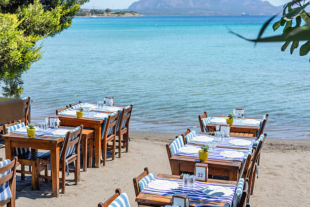 istock Waterfront dining area with white tables and clear blue water 2219940239