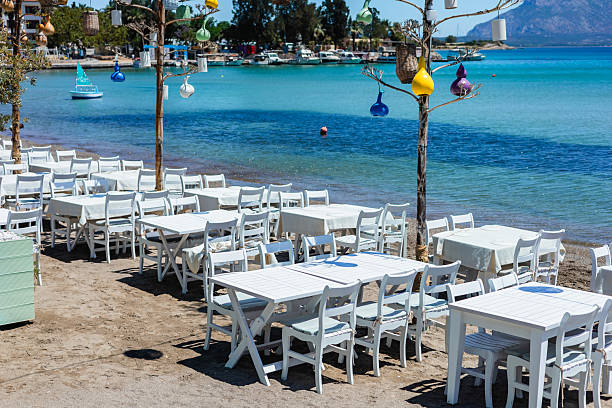 istock Waterfront dining area with white tables and clear blue water 2219941639