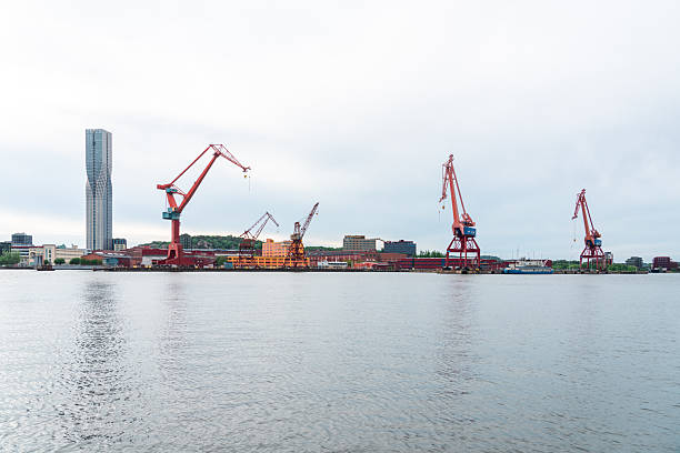 Gothenburg industrial harbour with its large cranes reflecting on the calm water under a cloudy sky