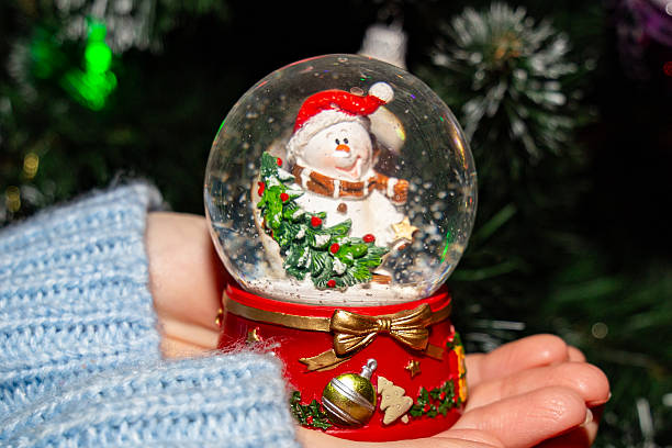 istock Snow globe with snowman held in hand, winter holiday decoration 2219942850