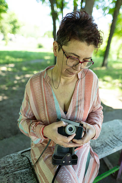 istock Happy woman adjusting her old-fashioned camera in the park. 2219943512