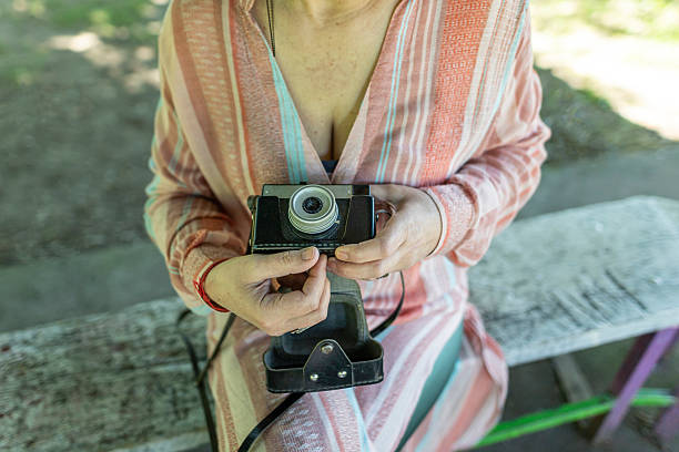 Happy woman adjusting her old-fashioned camera in the park.