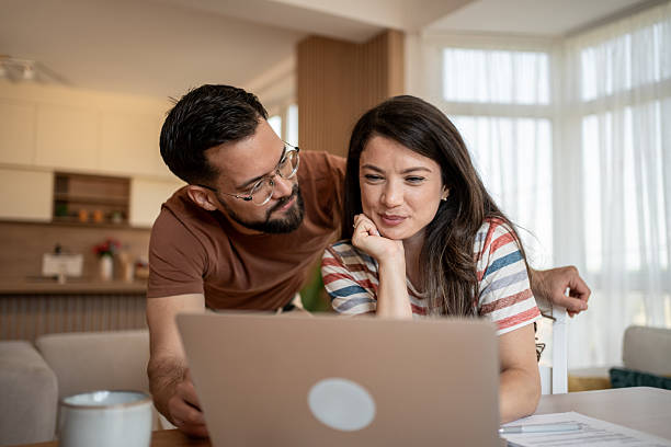 istock Couple working from home using laptop in living room 2219944641