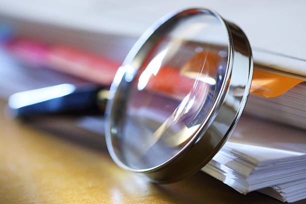 istock Magnifying Glass Leaning Against Stack Of Papers 2219949224