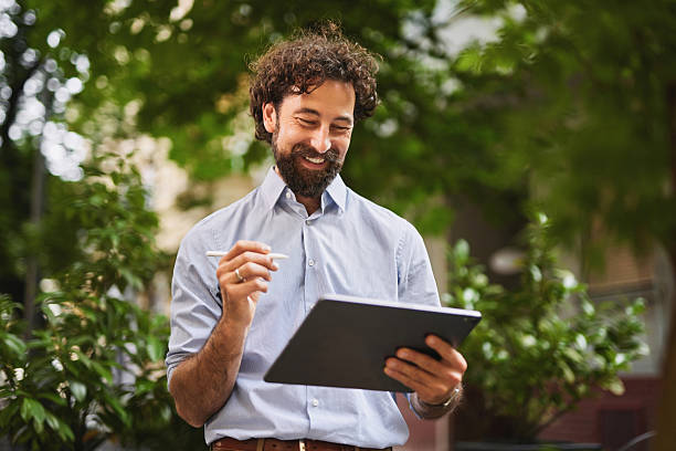 istock Smiling businessman using digital tablet and stylus pen outdoors 2219953057