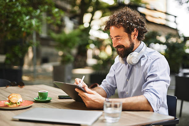 istock Happy businessman working on digital tablet at outdoor cafe 2219953552