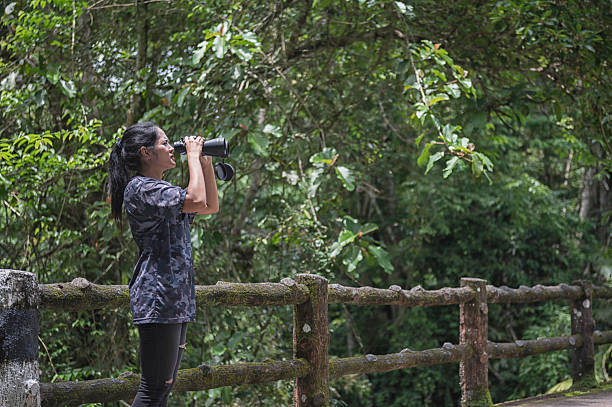 A man birdwatching in a lake with a telescope.