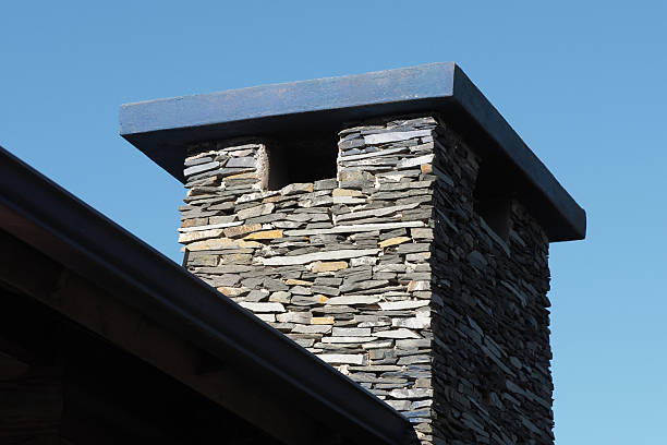 an old brick chimney of a factory boiler room with smoke on a blue sky background