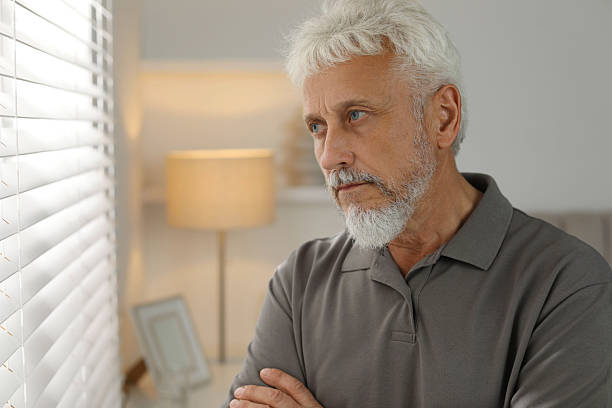 istock Lonely senior man looking out window indoors. Space for text 2219961029