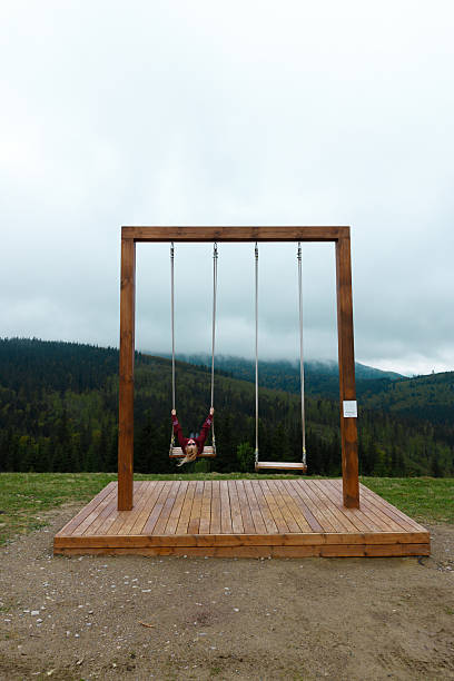 istock Swinging in the Mountains: Captivating Perspective from a Scenic Swing Set Surrounded by Lush Greenery under a Dramatic Sky Filled with Clouds 2219964177