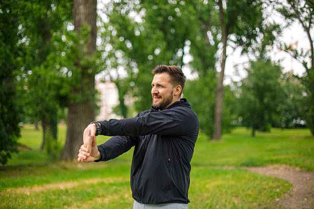 istock Runner stretching arms before running in a green park 2219965688