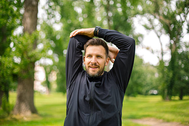 istock Young man stretching arms in a green park before running 2219965983