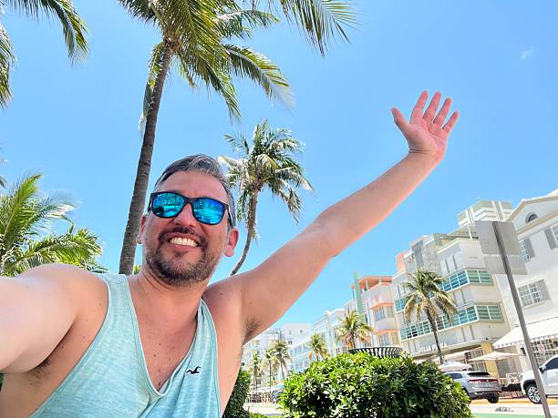 istock Tourist taking a selfie while open arms in Miami Beach, Florida, under palm trees 2219967748
