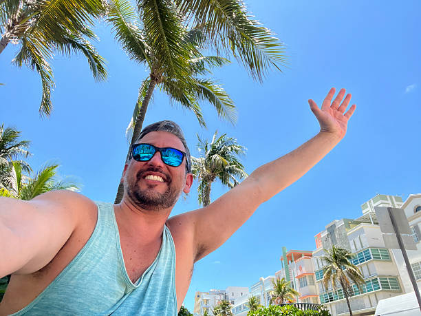 istock Tourist taking a selfie while open arms in Miami Beach, Florida, under palm trees 2219967757