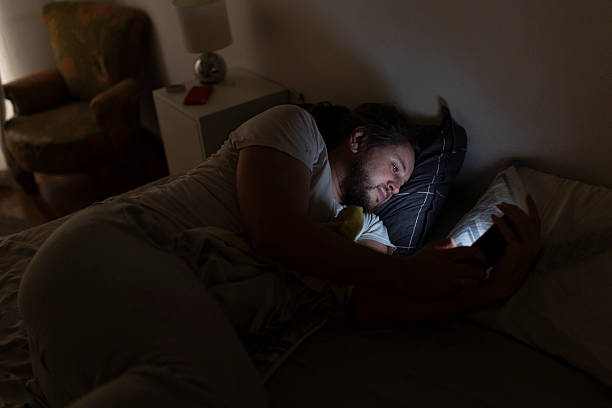 istock Man lying in bed at night using smartphone in dark room 2219967960