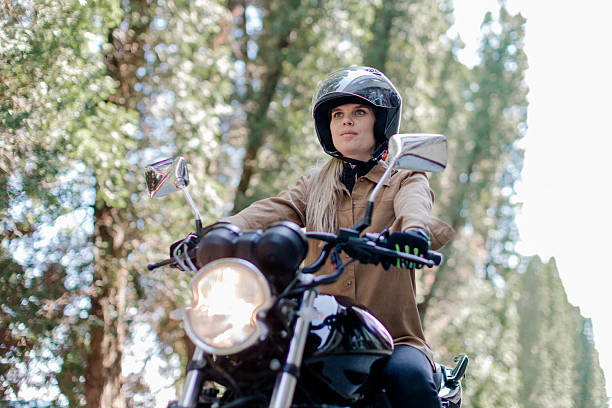 istock Young woman enjoying an adventurous ride on her motorcycle through a scenic forest path on a sunny day 2219968471