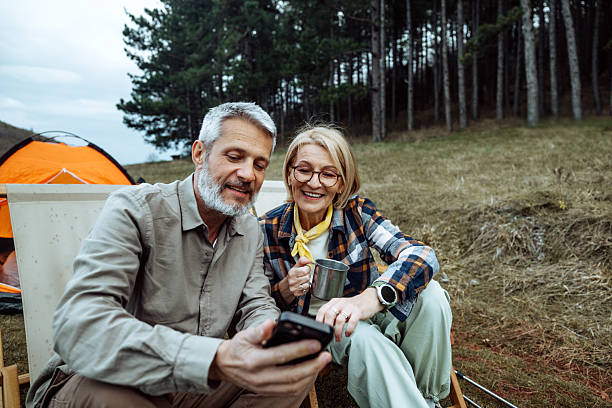 istock Smiling mature couple using smart phone while camping at the forest together 2219968850