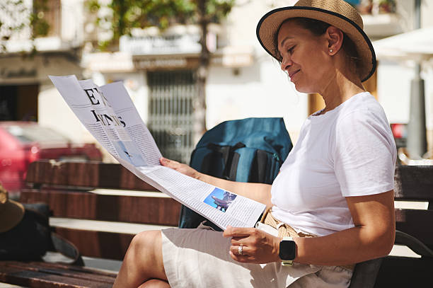 istock Smiling Woman Reading a Newspaper Outdoors in a Relaxed Urban Setting 2219969269