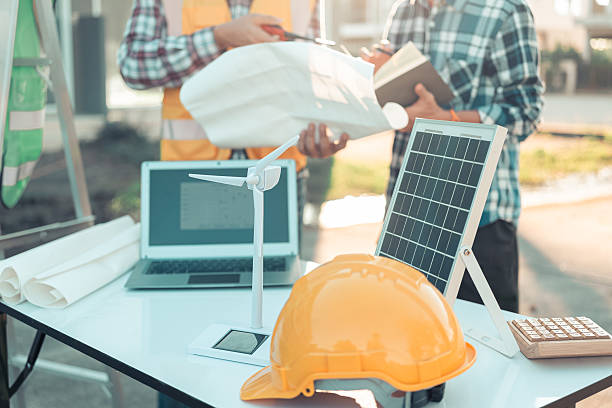 istock Two engineers work on wind turbine model components and discuss renewable energy sources of the solution with the computer. Wind turbine solar panel model to develop sustainable energy projects. 2219969635