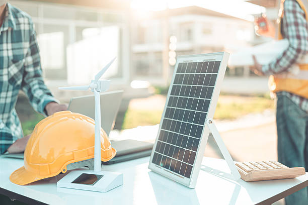 istock Two engineers work on wind turbine model components and discuss renewable energy sources of the solution with the computer. Wind turbine solar panel model to develop sustainable energy projects. 2219969638