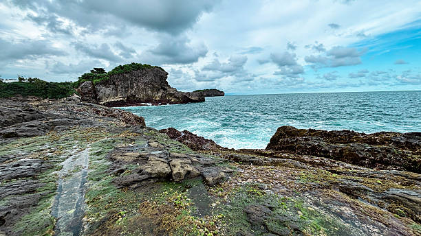 istock Rocky Seaside Cliff with Crashing Waves Under Cloudy Sky 2219973174
