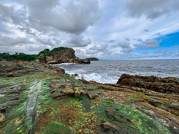 istock Rocky Seaside Cliff with Crashing Waves Under Cloudy Sky 2219973938