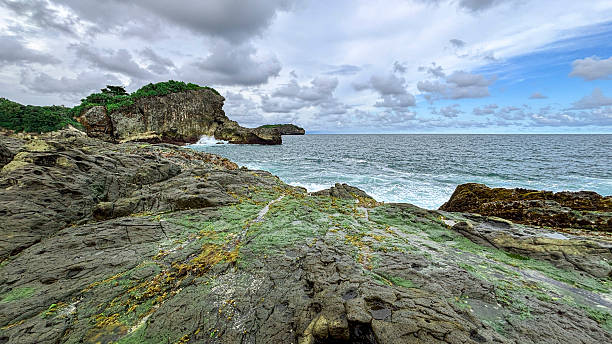 istock Rocky Seaside Cliff with Crashing Waves Under Cloudy Sky 2219974025