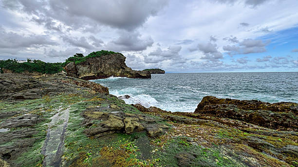 istock Rocky Seaside Cliff with Crashing Waves Under Cloudy Sky 2219974027