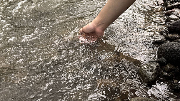 istock Human Hand Touching Clear Stream Water – Close-Up Connection with Nature 2219974504