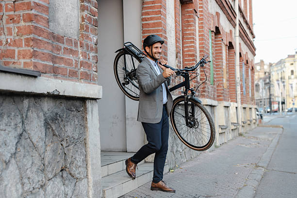 istock Businessman carrying bicycle outdoors in urban setting on his way to work 2219974824