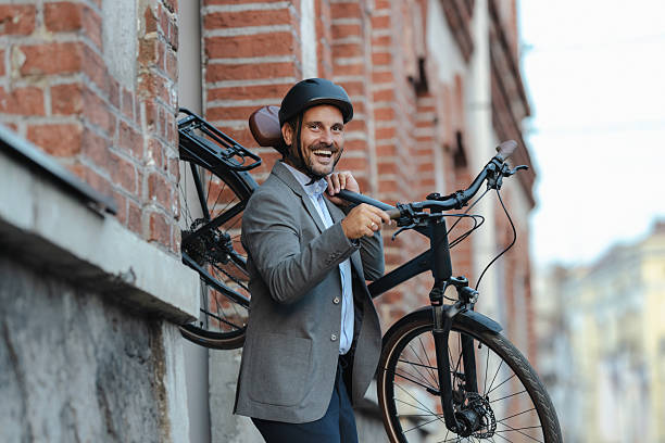 istock Professional man smiling while holding a bicycle outside a brick building 2219975278