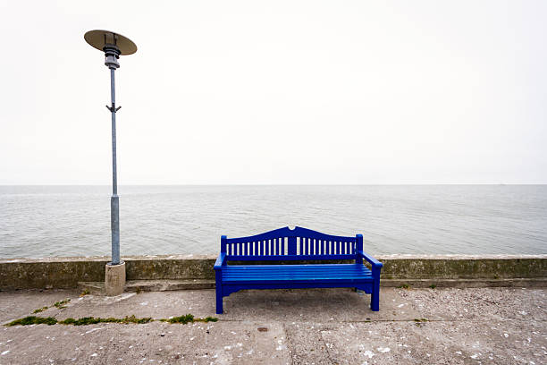 Lonely blue bench on a concrete pier under a cloudy sky in Nida Lithuania
