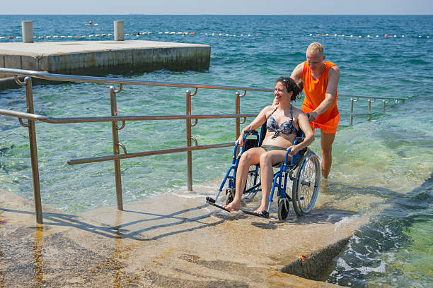 istock Woman with disability moving on an accessible beach ramp with a lifeguard help 2219981560