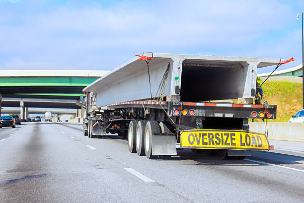 Large truck carrying oversize load concrete slabs on highway by overpasses