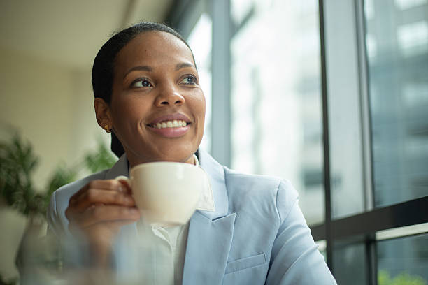 istock Smiling businesswoman drinking coffee and looking out the window 2219996552