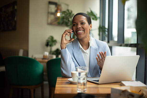 istock Businesswoman working remotely in a cafe, talking on phone and using laptop 2219997018