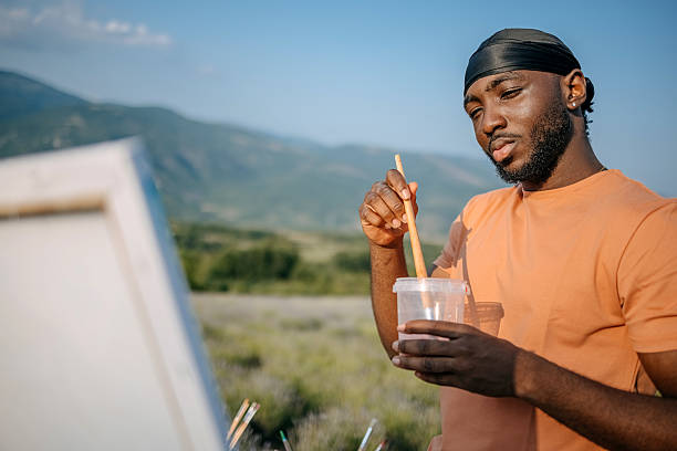 Young adult creating painting while standing in lavender field in nature